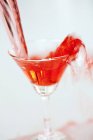 Martini vermelho sendo derramado em um copo — Fotografia de Stock