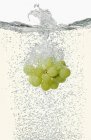 Grapes falling into champagne — Stock Photo
