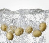 Patatas frescas en agua hirviendo - foto de stock