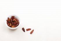 Getrocknete Chiliflocken in einer Schüssel und daneben auf weißem Hintergrund — Stockfoto