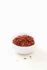 Elevated view of chilli flakes in a bowl and on white surface — Stock Photo