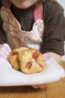Child holding freshly baked puff pastries on cloth — Stock Photo