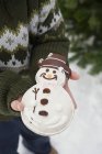 Niño sosteniendo galleta muñeco de nieve - foto de stock