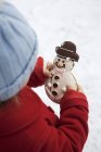 Cropped view of child holding snowman biscuit — Stock Photo