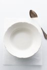 Closeup top view of an empty white plate on a piece of paper with a spoon — Stock Photo