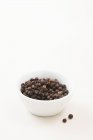 Granos de pimienta negro en tazón - foto de stock