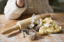 Cropped view of child near biscuit dough, cutters and rolling pin — Stock Photo