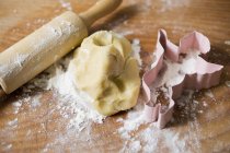 Dough, biscuit cutter and rolling pin — Stock Photo