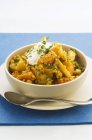 Curry de lentejas con crema agria en plato blanco con cuchara sobre fondo azul - foto de stock