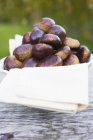 Chestnuts on cloth in white bowl — Stock Photo