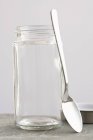 Closeup view of a spoon leaning against a screw-top jar — Stock Photo