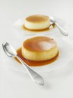 Primo piano vista di Crema caramello con cucchiai su piatti — Foto stock