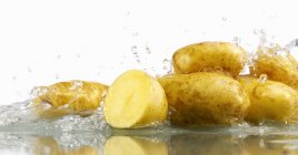 Patatas crudas en agua - foto de stock