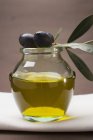 Schwarze Oliven auf einem Glas Olivenöl — Stockfoto