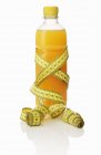 Bottle of juice with tape measure — Stock Photo