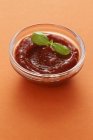 Tomaten-Chili-Sauce mit Basilikum über Orangenoberfläche — Stockfoto