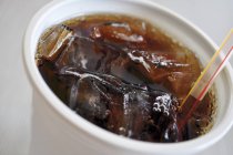 Primo piano vista della Cola in bicchiere di plastica con ghiaccio e paglia — Foto stock