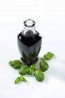 Vista elevada de una botella de vinagre balsámico y albahaca fresca - foto de stock