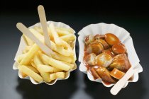Salchicha con salsa de tomate y patatas fritas - foto de stock