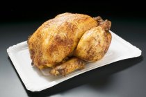 Whole roasted chicken on paper plate — Stock Photo