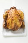 Целая жареная курица на бумажной тарелке — стоковое фото