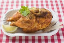 Half of roasted chicken in paper dish — Stock Photo