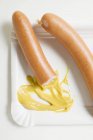 Frankfurters à la moutarde sur plaque de papier — Photo de stock