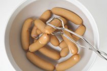 Lifting frankfurters out of water — Stock Photo