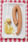 Frankfurters com mostarda em placa de papel — Fotografia de Stock