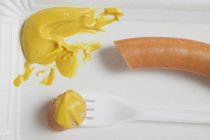 Frankfurter with mustard on paper plate — Stock Photo