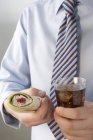 Vista de cerca del hombre en camisa y corbata sosteniendo envoltura comestible y cola - foto de stock