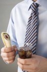 Closeup view of man in shirt and tie holding wrap and cola — Stock Photo