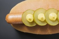 Hot dog with gherkins and mustard — Stock Photo