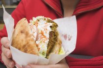 Person holding pita bread filled with falafel — Stock Photo