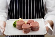 Koch hält Tablett mit Schweinemedaillons in der Hand — Stockfoto