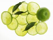 Lime intere e tagliate a fette con foglie — Foto stock