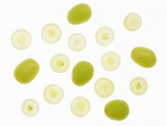 Vista superior de uvas verdes enteras y cortadas en rodajas sobre la superficie blanca - foto de stock