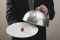 Butler servir tomate cerise sur assiette avec couvercle dôme, midsection — Photo de stock