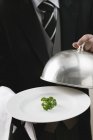 Cropped view of butler serving fresh parsley on plate with dome cover — Stock Photo