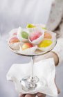 Closeup cropped view of woman holding marzipan fruits on stand — Stock Photo