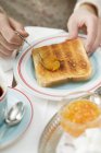 Mani Stendere marmellata di arance sul pane tostato sul piatto — Foto stock