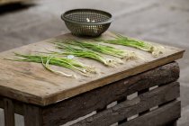 Spring onions lying on wooden table — Stock Photo