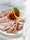 Slices of ham garnished with tomatoes — Stock Photo