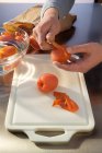Hombre manos Desollar tomates sobre tabla blanca de cortar - foto de stock