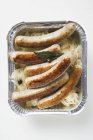 Sausages with sauerkraut in aluminium container — Stock Photo