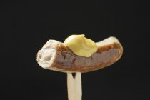 Колбаса с горчицей на деревянной вилке — стоковое фото