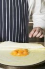 Closeup cropped view of person folding crepe with apricot filling — Stock Photo