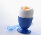Huevo cocido en taza de huevo azul - foto de stock