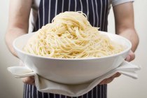 Man holding bowl of cooked spaghetti — Stock Photo