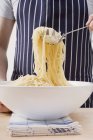 Hombre recogiendo espaguetis cocidos - foto de stock